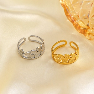 Adjustable stainless steel leaf rings in gold and silver finish on elegant silk fabric