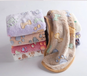 Close-up of soft coral fleece pet blankets with cute paw prints and bone patterns