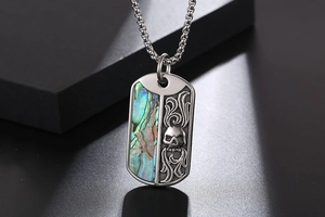 Macro detail of titanium steel dog tag pendant with skull relief and abalone shell inlay