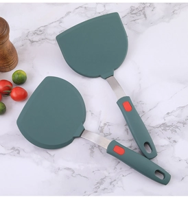 Deep green silicone spatulas with stainless steel handles on white marble surface