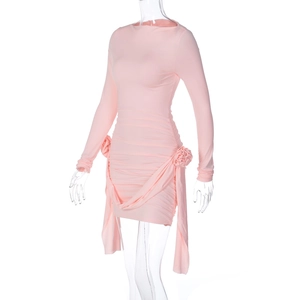 Détail d'une mini-robe rose à manches longues avec fleurs latérales et rubans pendants