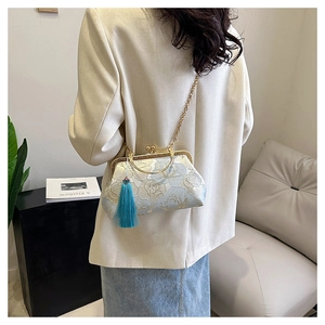Detail showing elegant floral embroidery and blue tassel on a shell-shaped chain bag