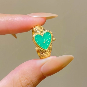 Macro shot of heart-shaped gold watch ring with green dial and elastic band