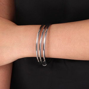 Detail of 3mm stainless steel triple interlocking bangle on woman's wrist with silver finish