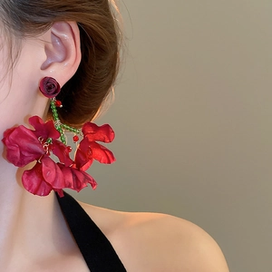 Detail of red fabric rose petal tassel earring worn by a model in a side profile shot
