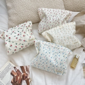 Détail de trousses à maquillage en coton matelassé à fleurs avec étiquette de marque