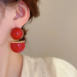 Gros plan de boucles d'oreilles perles rouges avec bord doré sur un modèle féminin