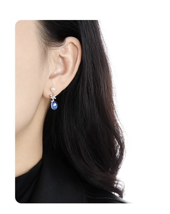 Detail of blue oval gemstone earrings with pearl and silver butterfly on model