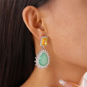 Macro shot of silver teardrop earrings with yellow and green stones on a model