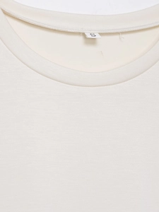 Detailaufnahme des Rundhalsausschnitts und des Größenetiketts S am beigen T-Shirt