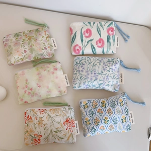 Flat lay of small floral cotton pouches with colorful zipper pulls and brand labels
