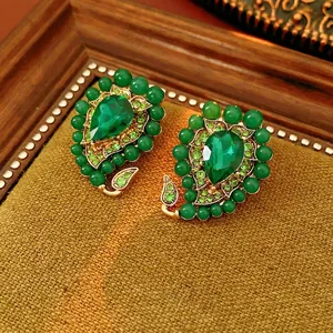 Vintage gold earrings with pear-shaped emerald green stones and bead details on moss fabric