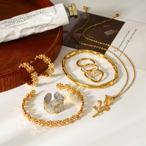 Elegant gold rose jewelry set with necklace earrings and bracelet on a wooden tray