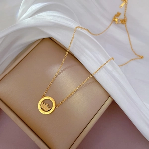 Close-up of gold titanium crown necklace with Lucky engraving on a jewelry box