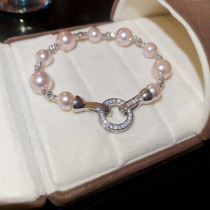Vue macro de perles rose-violet et d'un fermoir en argent serti de diamants sur écrin