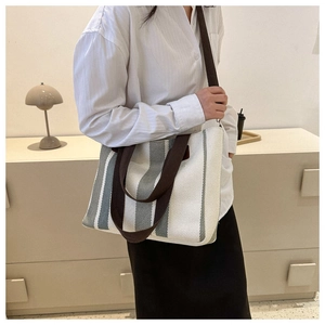 Lifestyle shot of grey striped canvas tote bag with adjustable brown shoulder strap