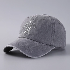 Detailed close-up of white sea turtle embroidery on a grey washed denim baseball cap