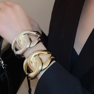 Detail of wide chunky chain link bracelets in polished gold and silver metallic finishes
