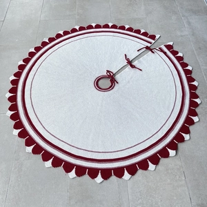 Dettaglio della gonna per albero di Natale in maglia crema con bordo rosso e lacci