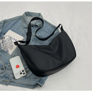 Close-up of black nylon crossbody bag styled on denim jacket with lifestyle accessories