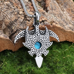 Vintage stainless steel eagle necklace with round turquoise stone on a rustic mossy bark background