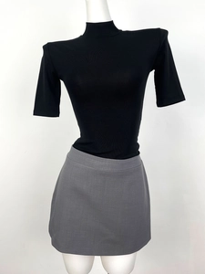 Detail of black rib-knit mock neck top and grey fitted skirt on a white mannequin