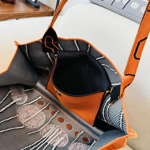 Detail of orange knitted tote bag showing interior black inner pocket and snap closure