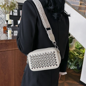 Chic cream studded crossbody bag with wide woven strap shown on a black suit jacket