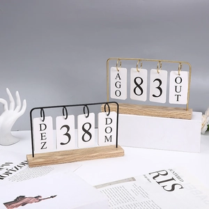 Nordic wooden flip calendar with black and gold metal frames on a minimalist desk