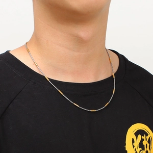 Gros plan d'un collier bicolore or et argent porté sur le cou d'un mannequin