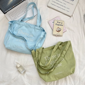 Detail view of large canvas tote bags with adjustable straps in blue and green colors