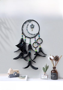 Detail of dream catcher featuring black feathers with moon and star woven center