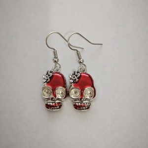Macro shot of gothic red enamel skull earrings with sparkling rhinestone eyes and hooks