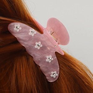 Pince à cheveux papillon marbre rose avec fleurs blanches sur cheveux auburn