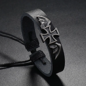 Close-up of vintage black braided leather bracelet with silver cross and bat wing detail