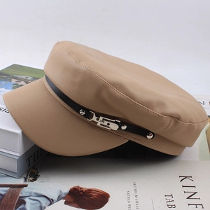 Detail view of beige PU leather newsboy hat with black strap and metallic buckle decoration