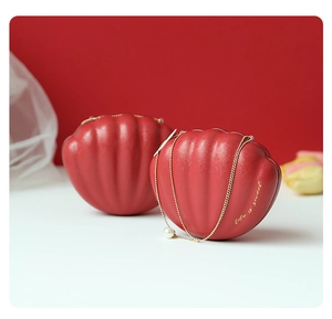 Detail of red shell-shaped wedding favor tins with gold life is sweet text and pearl chain