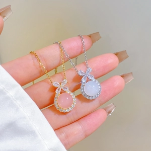 Macro detail of gold and silver bow necklaces with pink and white round gemstones