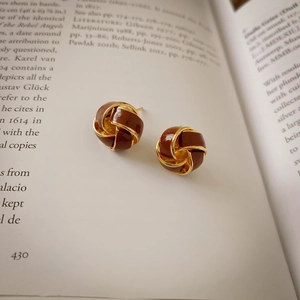 Retro twisted gold earrings with brown enamel finish displayed on an open vintage book