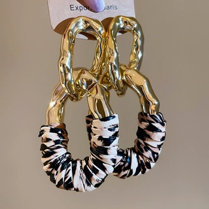 Macro shot of gold hammered metal hoop earrings with leopard print leather pendant charms