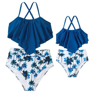 Detail of blue ruffled tankini top and palm print bikini bottoms for mother and daughter