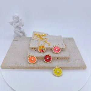 Macro view of colorful enamel fruit slice pendants on a premium stone display