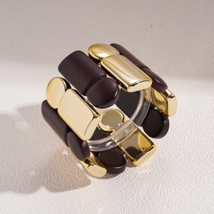 Detail of chunky geometric elastic bracelet with gold metal and brown matte blocks