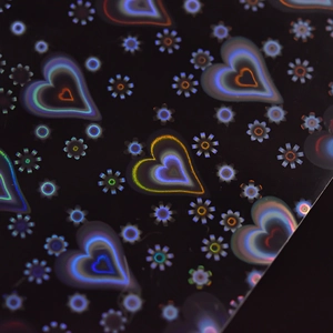 Detaillierte holografische Herz- und Gänseblümchen-Nagelaufkleber auf schwarzem Hintergrund