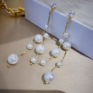 Detailed view of long gold tassel earrings with lustrous white pearls and sparkling zircon