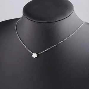 Macro shot of a silver floral pendant necklace on a black mannequin display stand