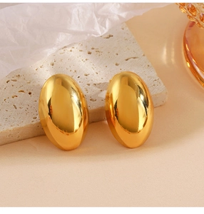 Macro shot of polished gold oval hoop earrings displayed on a natural textured stone