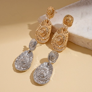 Boucles d'oreilles vintage dorées et argentées en forme de spirale sur marbre
