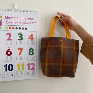 Detail of British plaid woolen tote bag with thick yellow webbing handle and metal snap