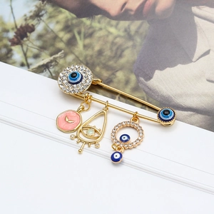 Evil eye safety pin brooch with sparkling crystals and blue charms on a golden metal base